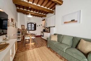 a living room with a green couch and a kitchen at Podere Fossaccio Casa Biancospino in Asciano