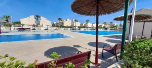 een zwembad met een bank en een parasol bij Manuel 217 en Gran Alacant in Gran Alacant