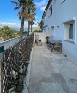 eine Terrasse mit Stühlen, einem Zaun und Palmen in der Unterkunft Appartement Vue mer La Croix Valmer in La Croix-Valmer