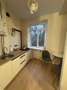 una cucina con lavandino, tavolo e finestra di Квартира a Dnipro