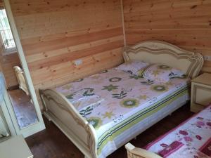 a bed in a room with a wooden wall at Guest House Chanba in Gudauta