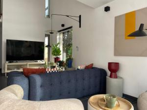 Una sala de estar con un sofá azul y un televisor en Villa Moderne - Sauna Privé, Spa chauffée, en Quatzenheim