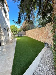 a yard with a stone wall and green grass at St Paul de Vence in Cagnes-sur-Mer