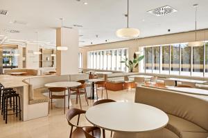 een restaurant met tafels, stoelen en ramen bij B&B HOTEL Granada Estación in Granada