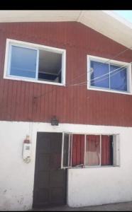 un edificio rojo y blanco con una puerta y dos ventanas en Cabaña Marina 1530, en Viña del Mar