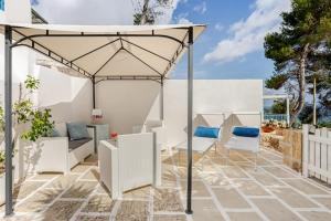 a patio with a white umbrella and white chairs at Seashell mare, natura e relax in Corsano