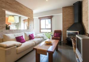 a living room with a white couch and a fireplace at Can Pitu in Alfondeguilla