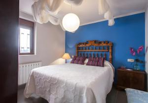 a blue bedroom with a large bed with purple pillows at Can Pitu in Alfondeguilla