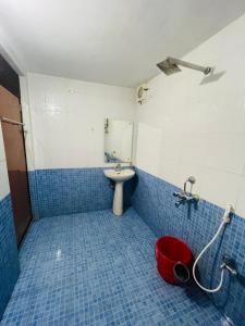 a blue tiled bathroom with a sink and a red bucket at Hamlet Beach Villas Alleppey in Alleppey
