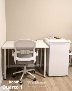 a white desk with a chair next to a refrigerator at We host in Costa da Caparica