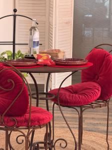 a table with two red chairs and a bottle of wine at La Cachette Fleurie in Hésingue