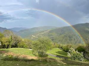 a rainbow over a field with a road and mountains at Total Peace and quiet on the top of the mountain, in Prats-de-Mollo-la-Preste