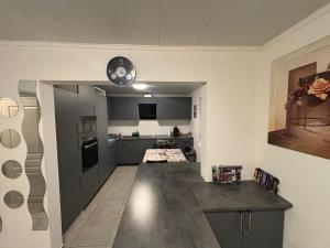 a kitchen with gray cabinets and a clock on the ceiling at Maison chaleureuse Calme et tranquillité assurés Parking privé in Geispolsheim