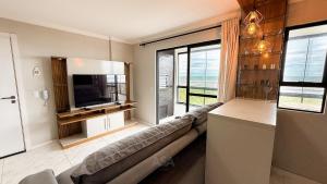 a living room with a couch and a large window at ASA | Pé na Areia | Frente-Mar Meia Praia | 2 Qtos in Navegantes