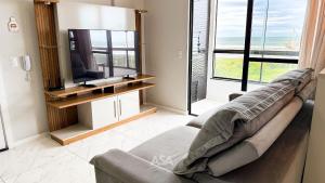 a living room with a couch and a tv at ASA | Pé na Areia | Frente-Mar Meia Praia | 2 Qtos in Navegantes