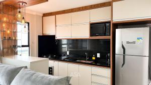 a kitchen with white cabinets and a white refrigerator at ASA | Pé na Areia | Frente-Mar Meia Praia | 2 Qtos in Navegantes