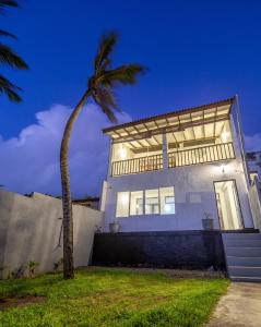 una palmera frente a una casa blanca en Merenza, en Unawatuna