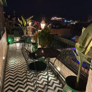 een patio met tafels en stoelen op een balkon in de nacht bij Riad Dar El bellar in Fès