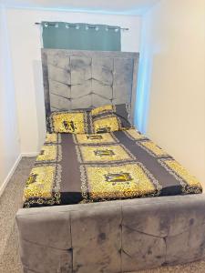 a bed with a large headboard and gold pillows at Goodness homes in Manchester