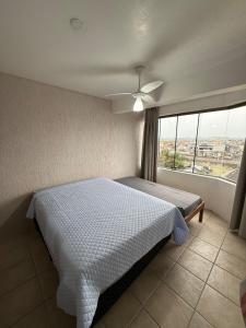 a bedroom with a bed and a large window at Entre o Mar e o Centro - A melhor Localização in Torres
