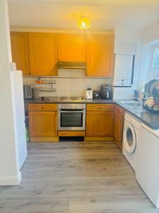 a kitchen with wooden cabinets and a washer and dryer at Goodness homes in Manchester