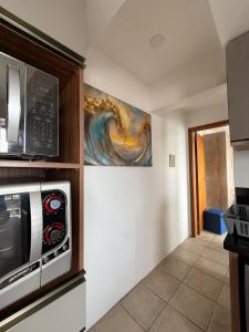 a kitchen with a microwave and a painting on the wall at Entre o Mar e o Centro - A melhor Localização in Torres