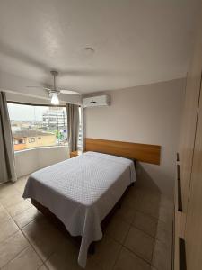 a bedroom with a bed and a large window at Entre o Mar e o Centro - A melhor Localização in Torres