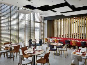 a restaurant with tables and chairs and windows at ibis Jeddah City Center in Jeddah