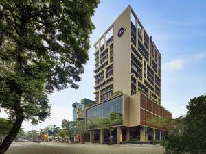 a tall building with a purple sign on it at Grand Mercure Hanoi in Hanoi
