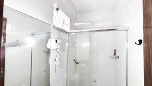 a white bathroom with a shower with a glass door at Arejar Hotel in Juruti