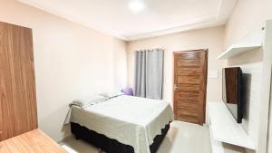a white bedroom with a bed and a television at Arejar Hotel in Juruti