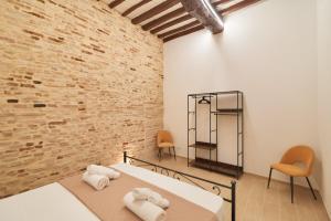 a bedroom with a bed and two chairs and a brick wall at AM10 - Modern flat in historic center in Perugia