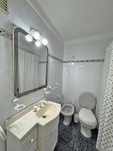 a bathroom with a sink and a toilet and a mirror at Departamento Bloom in Bahía Blanca