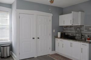 une cuisine avec des placards blancs et une porte blanche dans l'établissement Cozy Home, 19m to NYC, 10m to American Dream, à Wallington