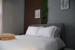 une chambre avec un lit avec des draps blancs et des oreillers dans l'établissement Cozy Home, 19m to NYC, 10m to American Dream, à Wallington