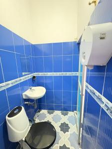 a blue tiled bathroom with a toilet and a sink at Hotel 7 in Cúcuta
