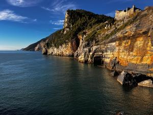 un acantilado con un castillo en lo alto, junto al agua en La Casetta del Vicolo, en La Spezia