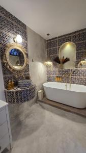 a bathroom with a tub and a mirror and a sink at Riad Lyabaïana privatisé, piscine et vue mer dans la médina in Tangier