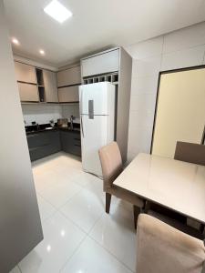 a kitchen with a refrigerator and a table and chairs at Refúgio Fraga Maia com Piscina e Estacionamento in Santo Antônio dos Prazeres