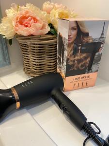 Ein Haartrockner steht auf einer Ablage neben einem Blumenkorb. in der Unterkunft La petite maison in Solesmes