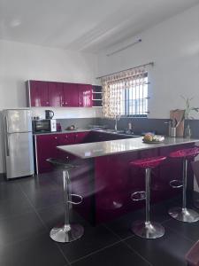 une cuisine avec des armoires violettes et un comptoir avec des tabourets de bar dans l'établissement Soley, à Port-Louis