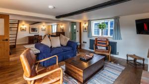 a living room with a blue couch and a table at Ramsbury Cottage in Ramsbury