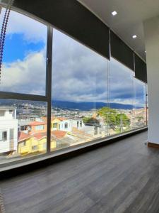 a room with a large window with a view of a city at Suite de 4 camas cerca de UTPL y centro in Loja