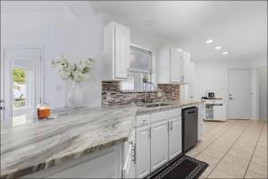a kitchen with white cabinets and a marble counter top at Homes in Prosper in Prosper