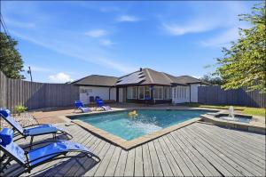 a swimming pool with blue chairs and a house at Homes in Prosper in Prosper