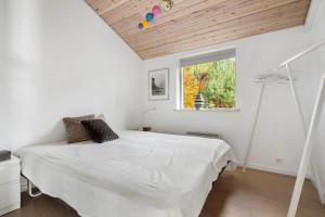 a bedroom with a white bed and a window at 2502-Nexo-Gubbegardsvejen-31 in Neksø