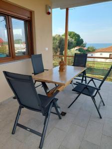 einen Holztisch und vier Stühle auf einer Terrasse in der Unterkunft Villa Anastasia 1ος Όροφος Εξοχικής Παραθαλάσσιας Κατοικίας Νέα Ηράκλεια Χαλκιδικής in Nea Iraklia