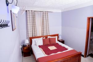 Un dormitorio con una cama con una manta roja encima. en M3 Stella Hotel, en Kampala