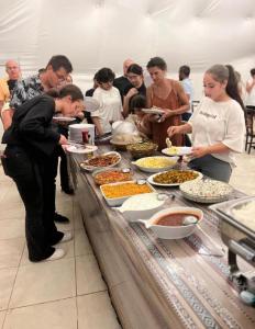 a group of people standing around a buffet table with food at Rum Aranda camp &Bubbles Hotel in Wadi Rum +66 photos