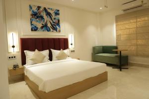a bedroom with a large bed and a green chair at Hotel Amber Inn in Prayagraj